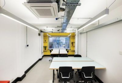 Spacious open-plan office with white workstations, exposed ductwork, and bright yellow accent walls.