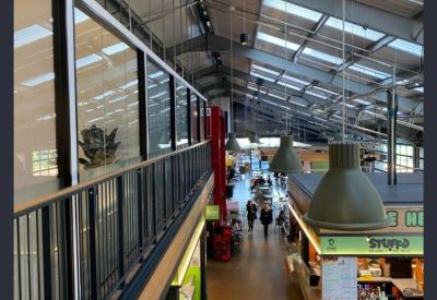 High-angle view of a bright industrial-style food hall and communal market space.