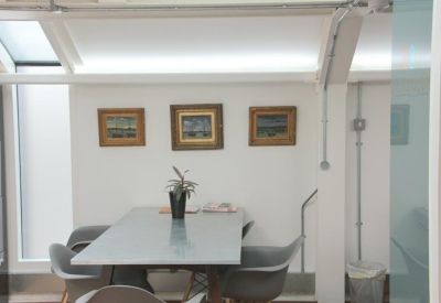 Small meeting room with a grey table, matching chairs, and three framed pictures on the wall.