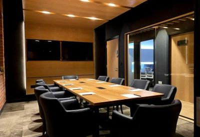 Meeting room with a long wooden table and ergonomic black chairs.