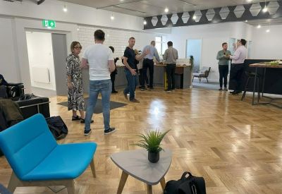 Spacious communal lounge area with wood floors and a bright blue chair.