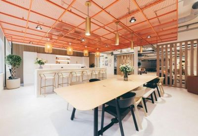 Vibrant communal kitchen and lounge area with an orange mesh ceiling and long wooden dining table.