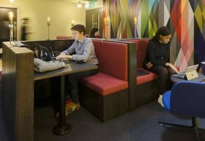 Communal breakout area with red booth seating and colorful geometric wall art.