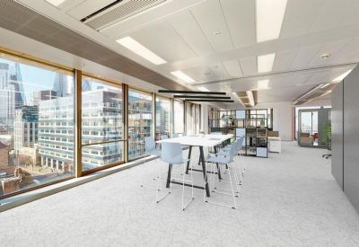 Bright open-plan office area with a white high table and floor-to-ceiling windows.