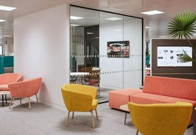 Lounge area featuring colorful peach and yellow armchairs near a glass-walled room.