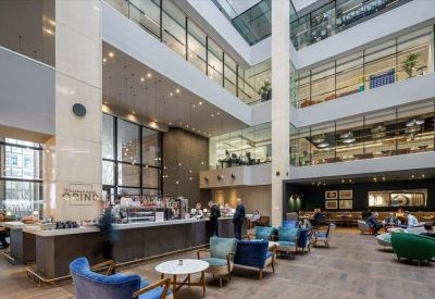 Spacious multi-story atrium communal area with a cafe bar, lounge seating, and internal windows.