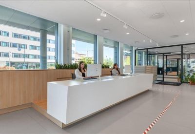 Bright reception area with a long white minimalist front desk and large windows.