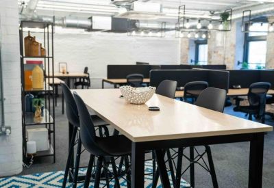 Communal break area with high tables, black stools, and a patterned rug.