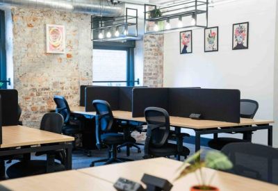 Workspace area with individual desks separated by black privacy screens and brick pillars.