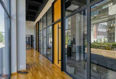 Bright hallway with floor-to-ceiling glass partitions and wooden flooring.