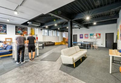 Spacious recreation room with ping pong tables and white sofas.