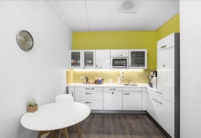 Bright communal kitchen and dining area with white cabinetry and a bold yellow accent wall.