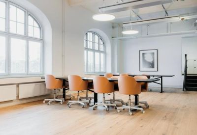 Sun-drenched conference room with a long table, tan leather chairs, and large windows.