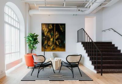 Lounge area with designer chairs, a large abstract painting, and a striped rug.