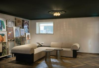 Lounge area with a cream modular sofa, dark ceiling, and a cluster of art pieces.