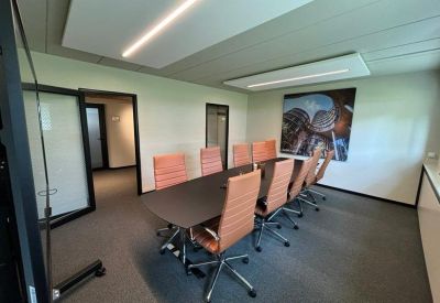 Professional meeting room with a dark table, tan leather chairs, and overhead acoustic panels.