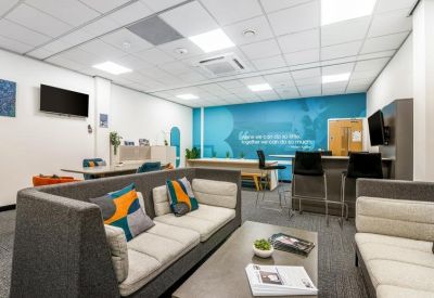 Modern breakout area with grey sofas, colorful cushions, and a blue feature wall mural.
