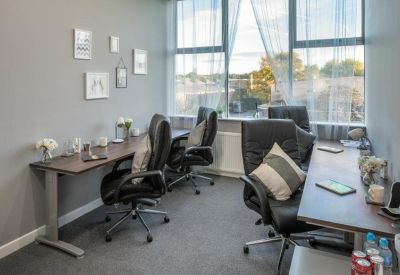 Private office suite with three leather chairs, desks, and large windows providing natural light.