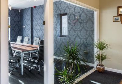 Elegant meeting room with patterned blue wallpaper, a wooden table, and indoor plants.
