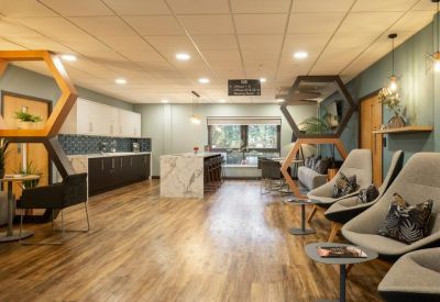 Spacious breakout area with a kitchen island, modern armchairs, and honeycomb shelving.