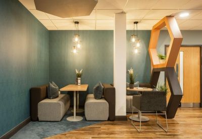 Cozy seating booths with teal feature walls and unique hexagonal wooden partitions.