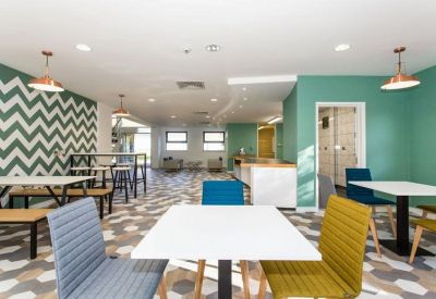 Spacious communal breakout area with chevron-patterned walls and colourful seating.