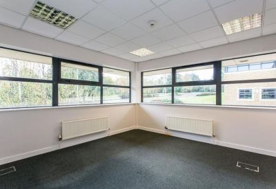 Empty corner office suite with large windows and grey carpeting.