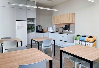 Kitchen area with light wood cabinets, white appliances, and recycling bins.