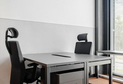 Two-person office workstation with grey desks and ergonomic black chairs.