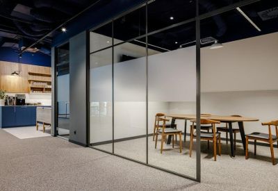 Small meeting room with an oval wooden table and blue industrial ceiling.