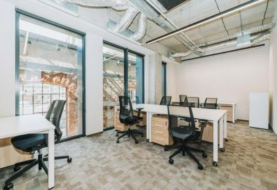 Multi-desk office space with wooden storage units and large windows.