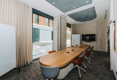 Conference room with a long wooden table and brown leather chairs.