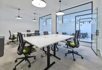 Bright four-person office suite with ergonomic green chairs and glass partitions.