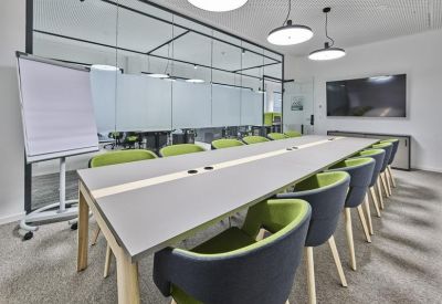 Long boardroom table with stylish grey and green bucket chairs and a whiteboard.