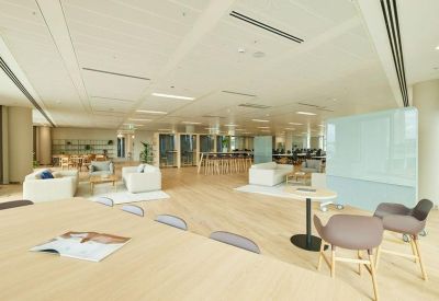 Bright coworking space with white sofas, wooden floors, and a movable whiteboard.