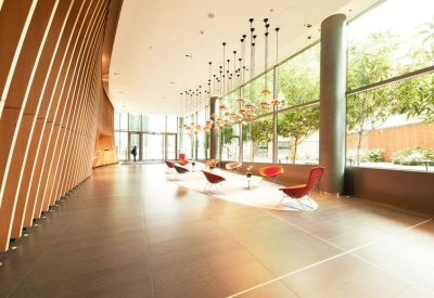 Modern building lobby with a curved wood-slatted wall and designer red armchairs.
