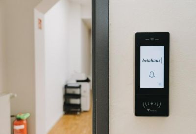 Digital building directory and intercom mounted on a white wall.