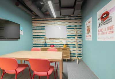 Small meeting room with a wooden table, coral chairs, and patterned accent wall.