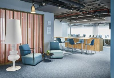 Breakout area featuring blue lounge chairs and a tall white floor lamp.