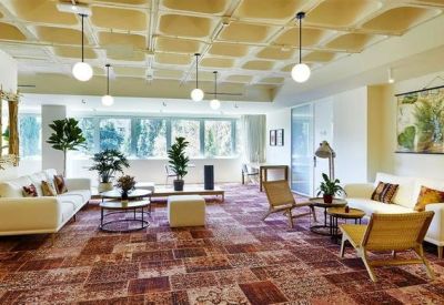 Modern open-plan office with white desks, ergonomic chairs, and large windows.