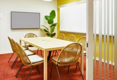 Small break-out room with high-top seating, blue carpet, and a green accent wall.