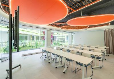 Training room featuring long white tables, blue chairs, and unique orange ceiling baffles.