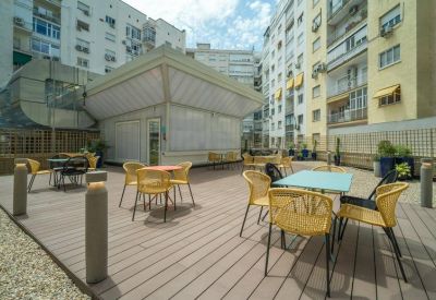 Outdoor wooden terrace with yellow wicker chairs and cafe tables.
