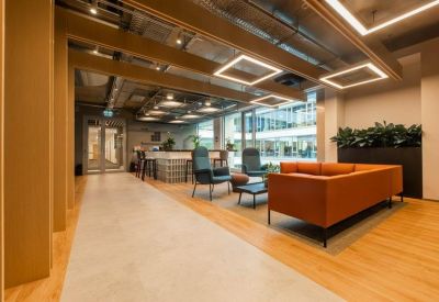 Breakout lounge with an orange sofa, blue armchairs, and warm wooden accents.