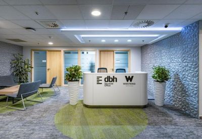 Bright reception area at Váci str 1-3 with a white curved desk, branded signage, and green circular carpet.