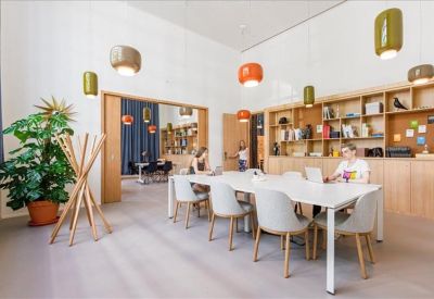 Atrium-style communal area with a long dining table under a modern architectural steel structure.