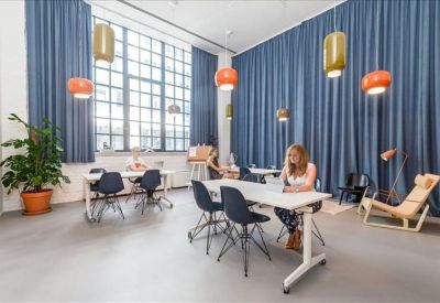 Bright workspace with blue curtains, hanging globe lights, and multiple desks for focused work.