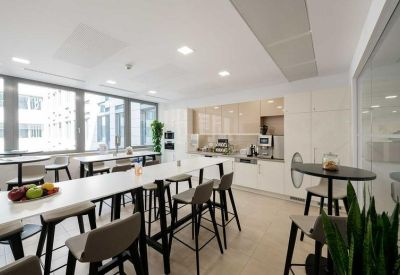 Spacious communal dining area with long white high-top tables and a modern kitchenette.