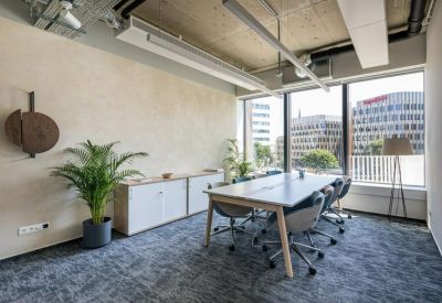 Modern meeting room with large windows, wooden conference table, and indoor plants.