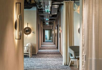 Long office corridor with patterned carpet and designer wall lighting.
